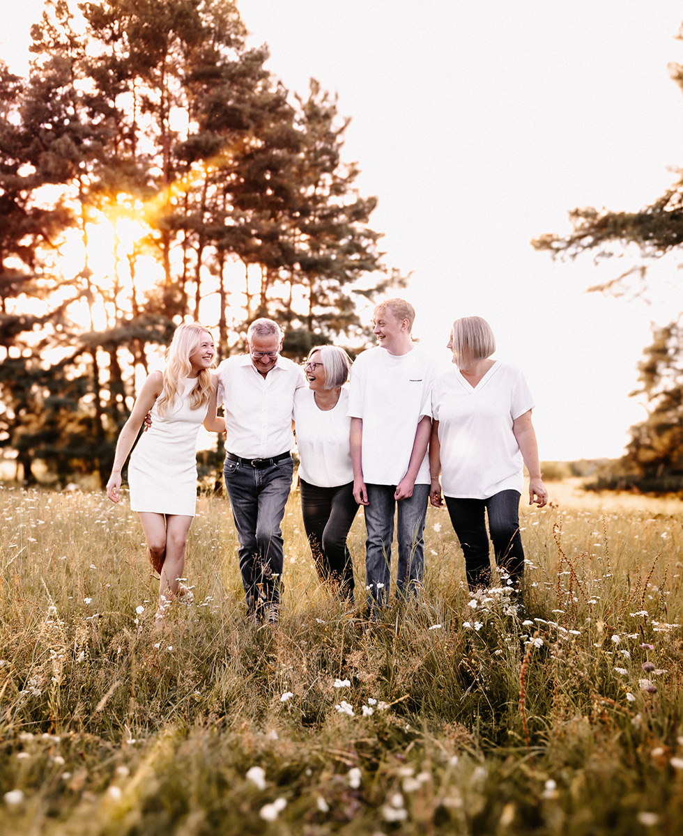Mehrgenerationen-Familie läuft lachend durch eine Wiese im Sonnenuntergang – natürliche Familienfotografie Nürnberg Schwabach Roth Fürth