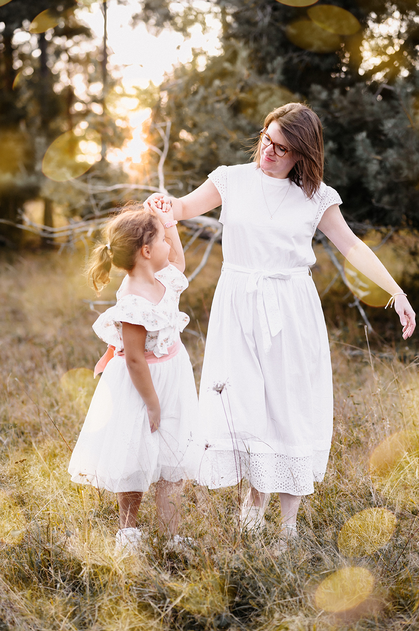 Mutter und Tochter tanzen im Sonnenlicht auf einer Wiese – natürliche Familienfotografie Nürnberg Schwabach Roth Fürth