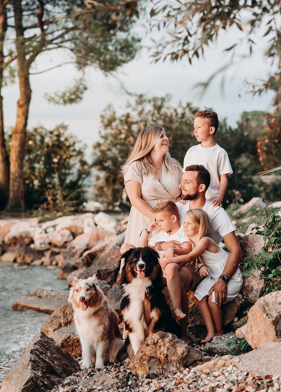Familie mit Kindern und zwei Hunden sitzt gemeinsam am Wasser im Sonnenlicht – natürliche Familienfotografie von Stefanie Cypris Fotografin Nürnberg Schwabach Roth Fürth