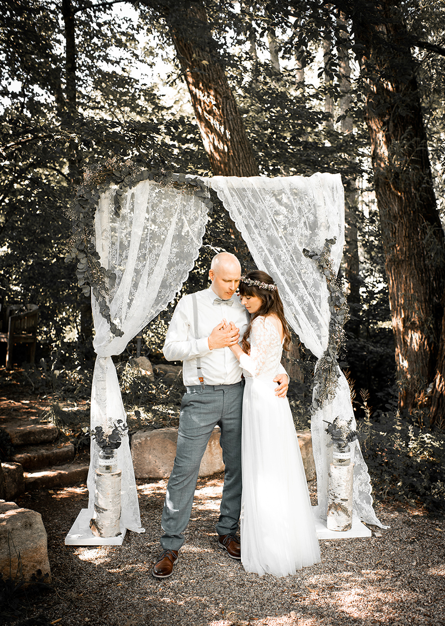 Brautpaar steht unter einem dekorierten Traubogen im Wald bei einer freien Trauung – natürliche Hochzeitsfotografie von Stefanie Cypris Fotografin Nürnberg Schwabach Roth Fürth