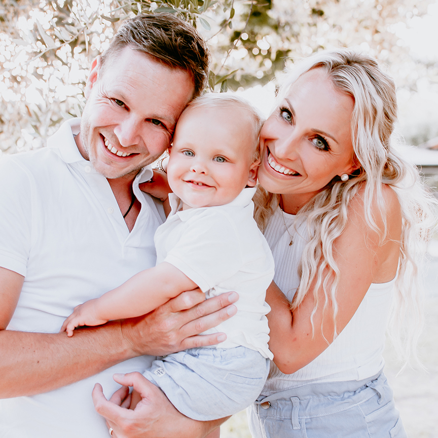 Glückliche Familie mit Kind im Arm lächelt in die Kamera im natürlichen Licht – Familienfotografie von Stefanie Cypris Fotografin Nürnberg Schwabach Roth Fürth