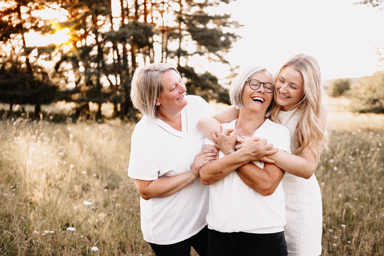 Drei Frauen aus verschiedenen Generationen lachen gemeinsam im Sonnenlicht im Freien – natürliche Familienfotografie von Stefanie Cypris Fotografin Nürnberg Schwabach Roth Fürth