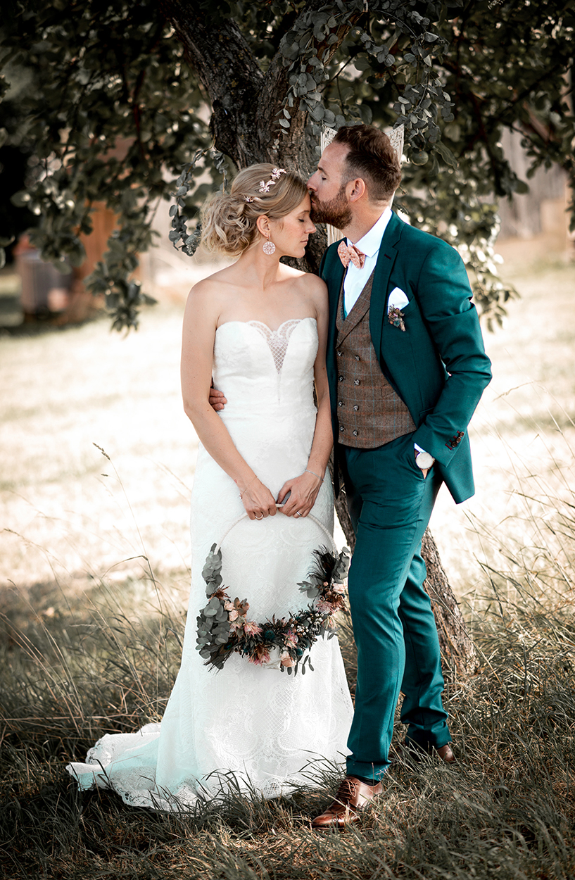 Brautpaar steht unter einem Baum, Bräutigam küsst die Stirn der Braut – natürliche Hochzeitsfotografie von Stefanie Cypris Fotografin Nürnberg Schwabach Roth Fürth