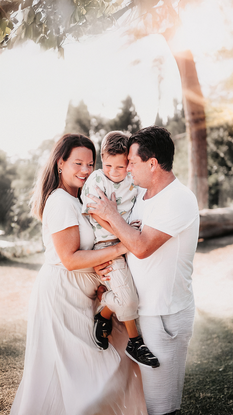 Eltern halten ihr Kind im Arm und lachen gemeinsam im Sonnenlicht – natürliche Familienfotografie von Stefanie Cypris Fotografin Nürnberg Schwabach Roth Fürth